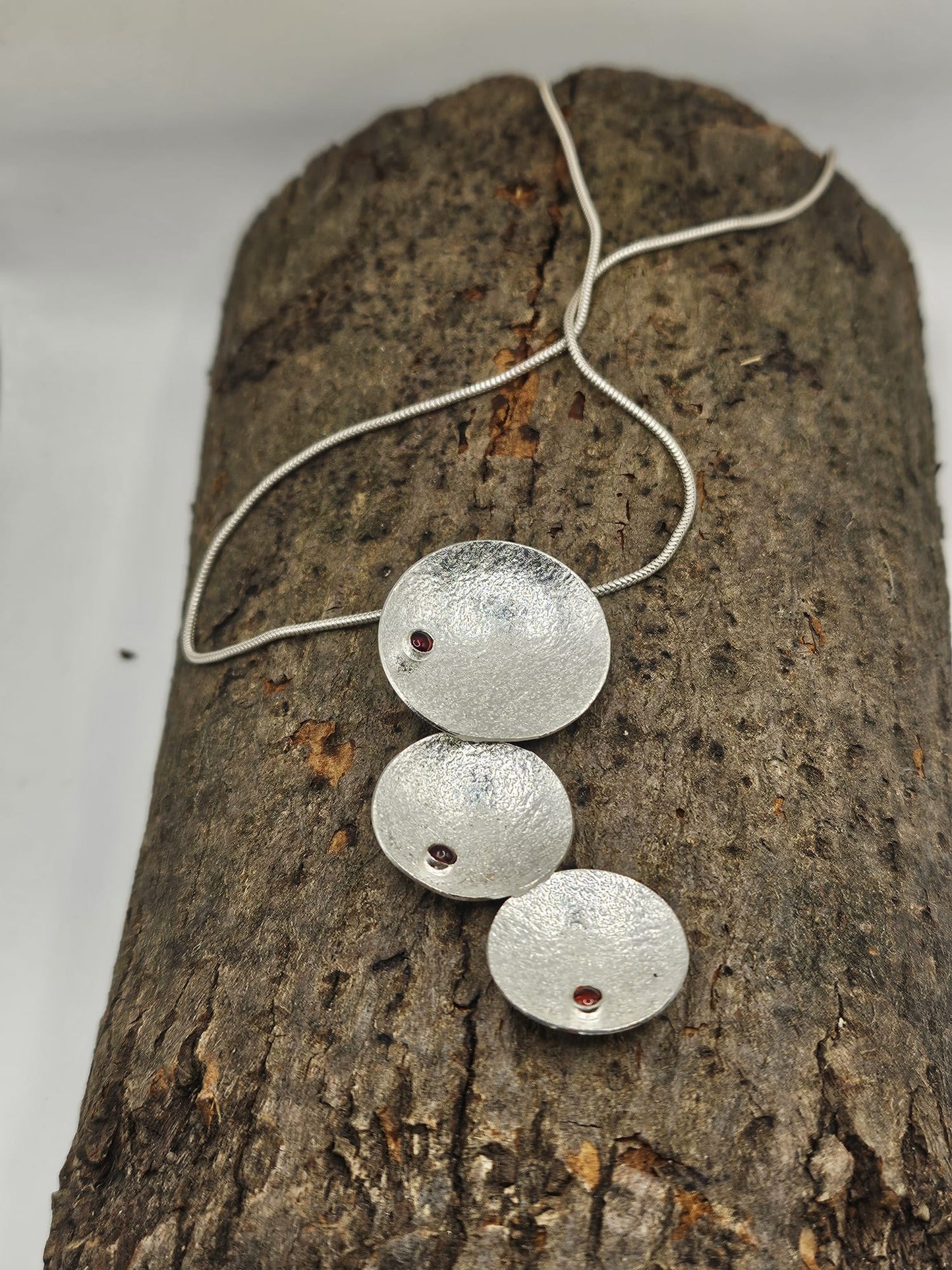 sterling silver circle pendant with red garnets. on a silver snake chain